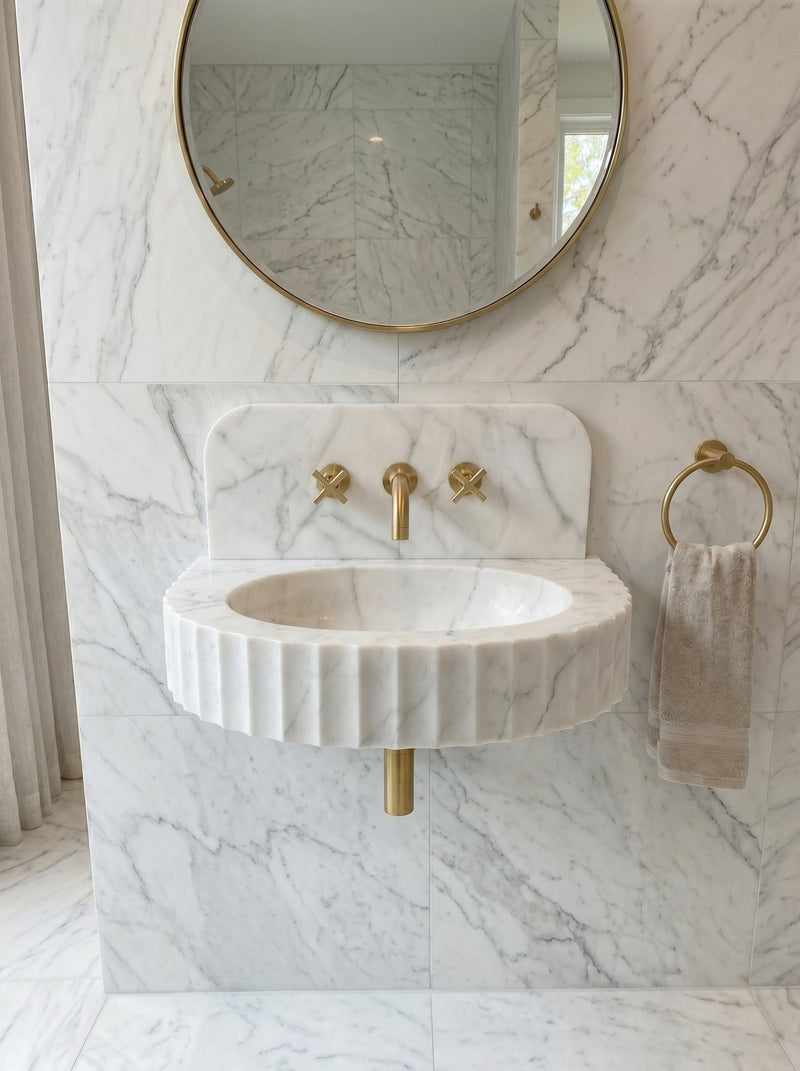 Marble sink with gold fixtures in a bathroom setting. Carrara White Marble Wall-mount Bathroom Sink Fluted Front (W)16" (L)24" (H)6"