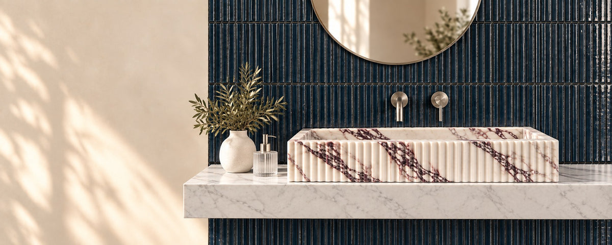 Fluted marble vessel sink on a marble shelf against a navy fluted glazed terracotta tile wall