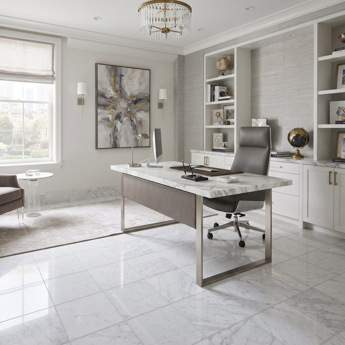 A modern home office featuring a large desk with a white marble top and brushed steel frame, paired with a dark gray leather office chair. The room has light gray marble floors, white built-in shelves, and a large abstract painting on the wall.