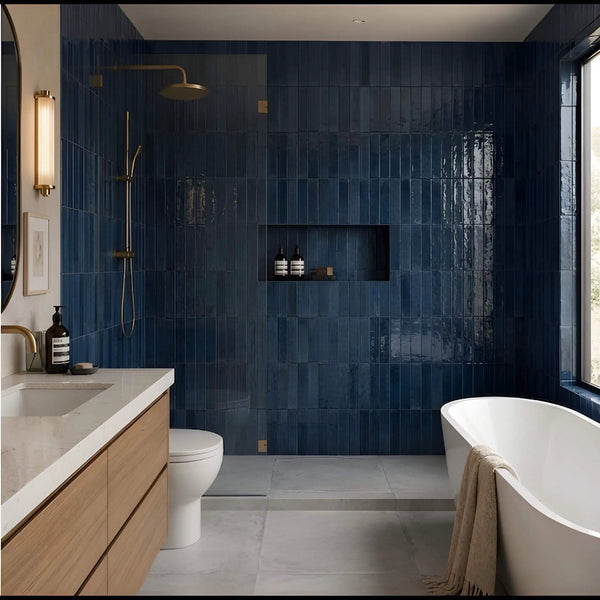Bathroom with glossy navy blue subway tile walls, freestanding tub and brass fixtures