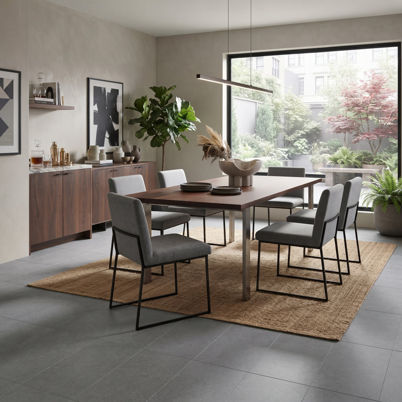 A modern dining room scene featuring a rectangular wooden dining table with six gray upholstered chairs on a woven jute rug, set in a contemporary interior with a large window and sideboard.