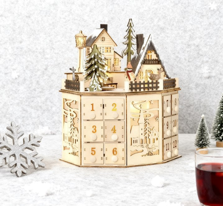 Wooden Christmas Advent Calendar with Village Scene and 24 Drawers, Natural, installed in a room